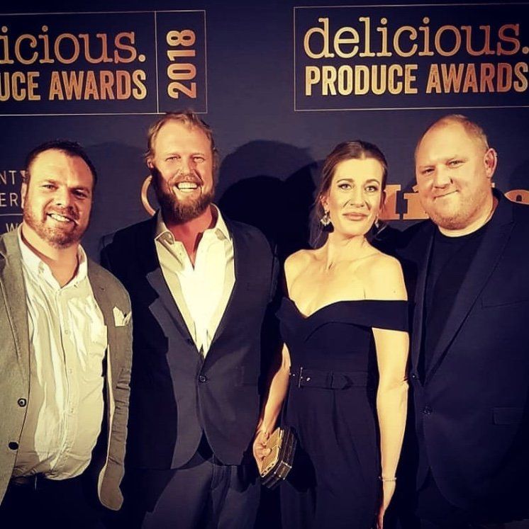 A group of people standing in front of a sign that says delicious produce awards