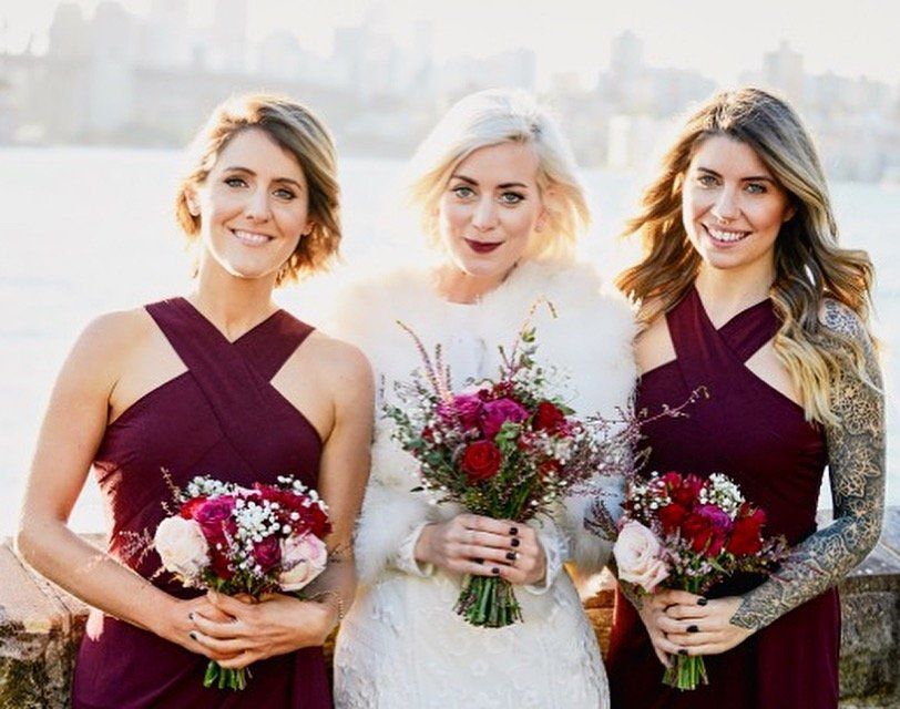 A bride and her bridesmaids are posing for a picture while holding bouquets of flowers.