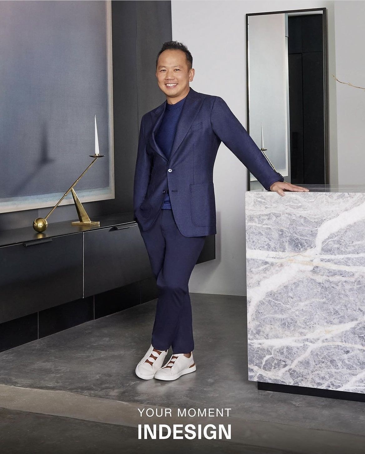 A man in a suit is leaning against a counter with the word indesign on the bottom