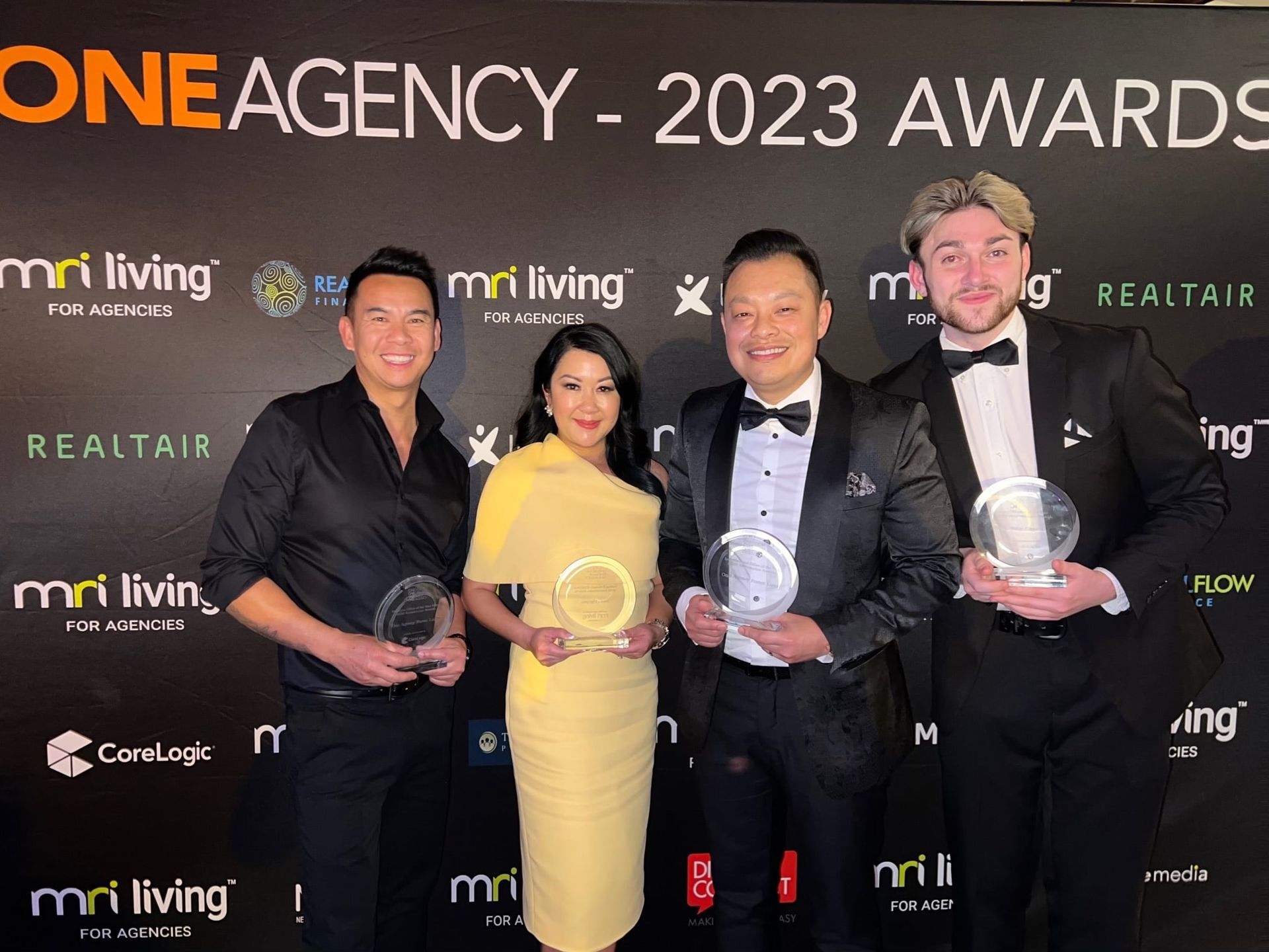 A group of people standing in front of a wall that says one agency 2023 awards