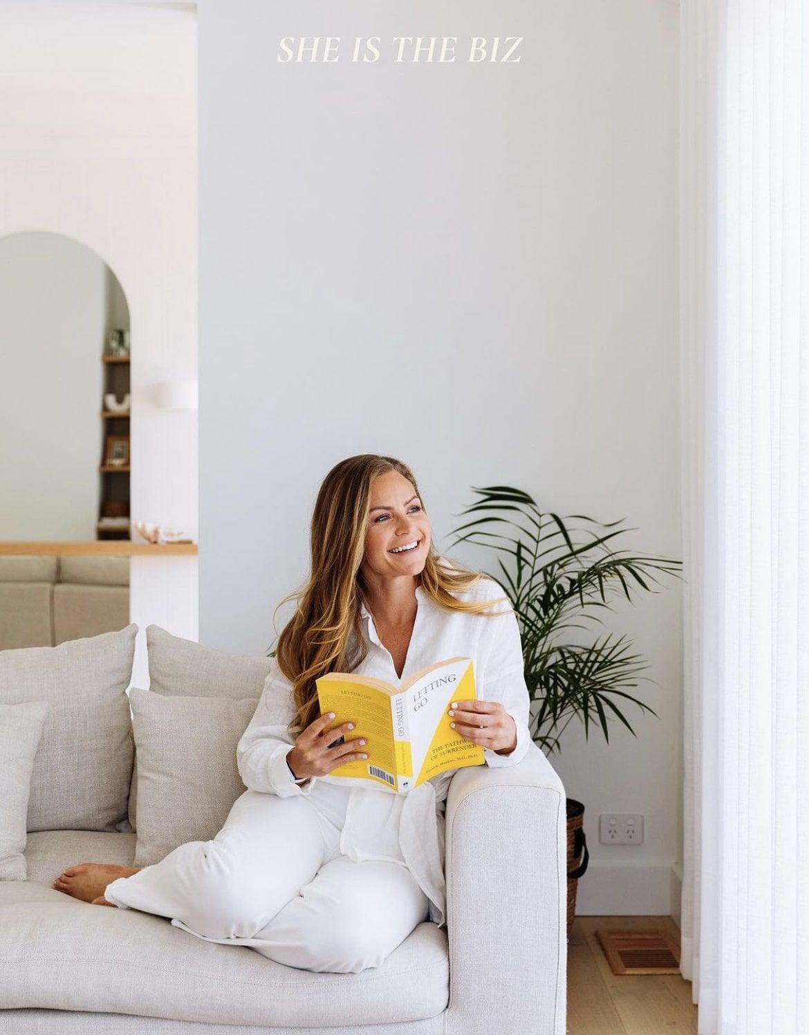 A woman is sitting on a couch reading a book