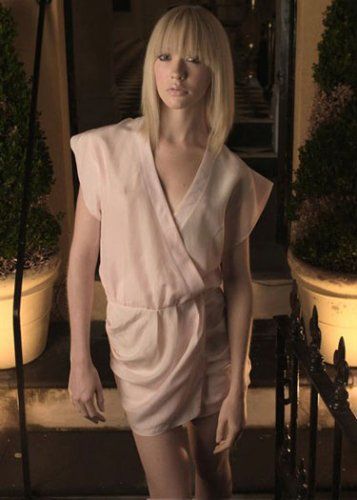 A woman in a white dress is standing in front of potted plants