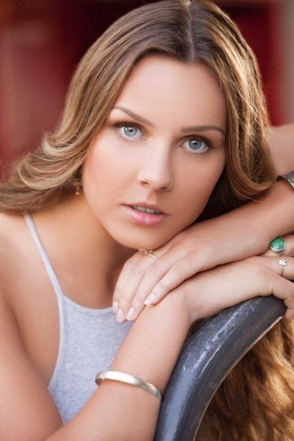 A woman is leaning on a chair with her head resting on her arm.