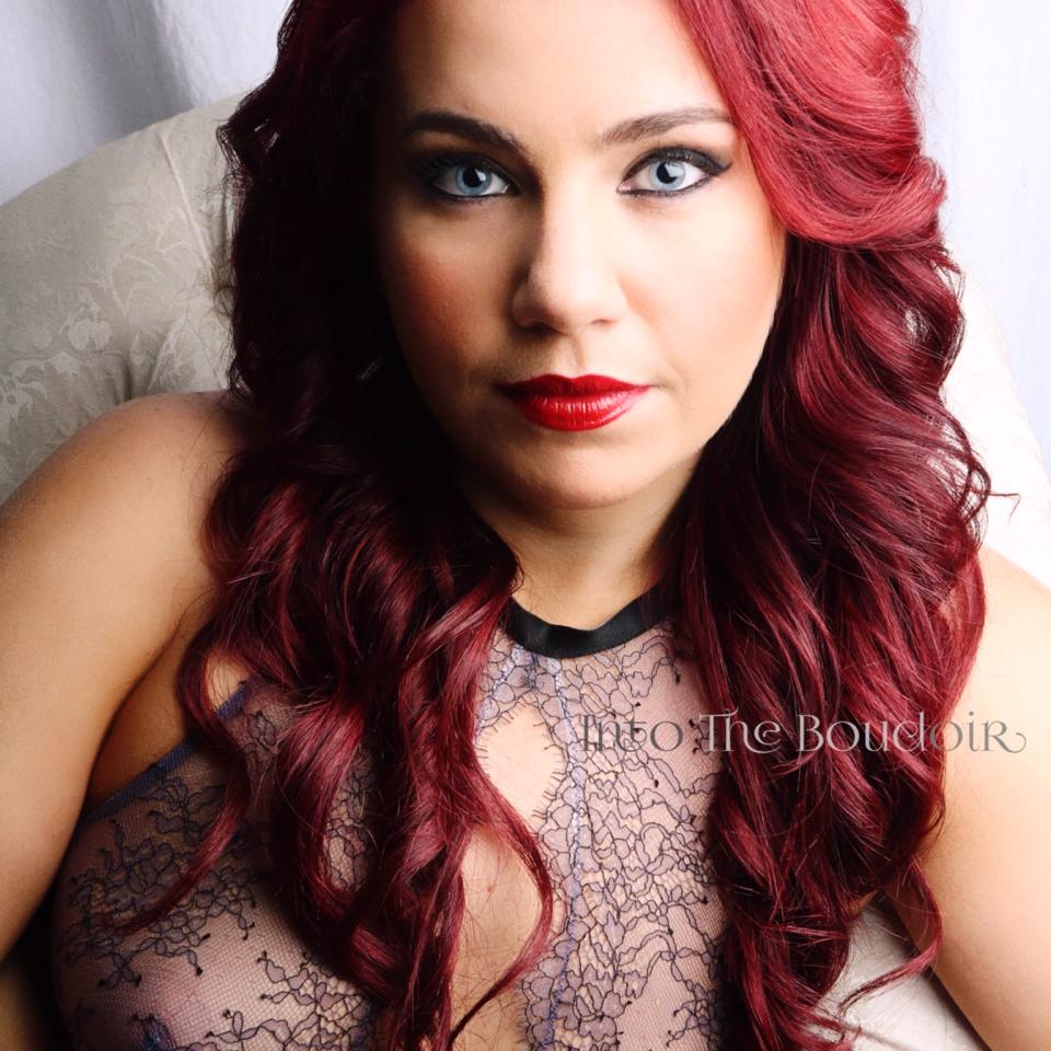 A woman with red hair is wearing a lace top
