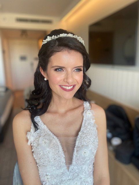 A woman in a wedding dress is smiling and wearing a headband.