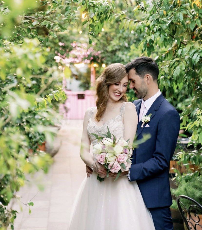 A bride and groom are posing for a picture in a garden.