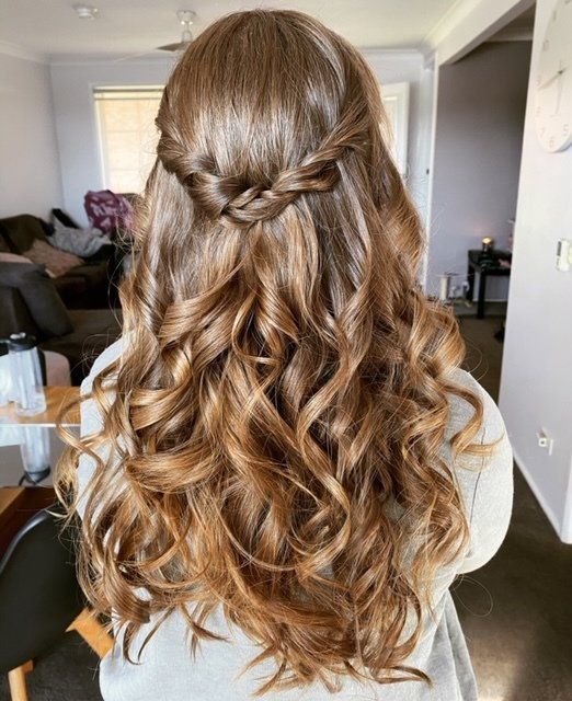 A woman with long brown hair is wearing a half up half down hairstyle.