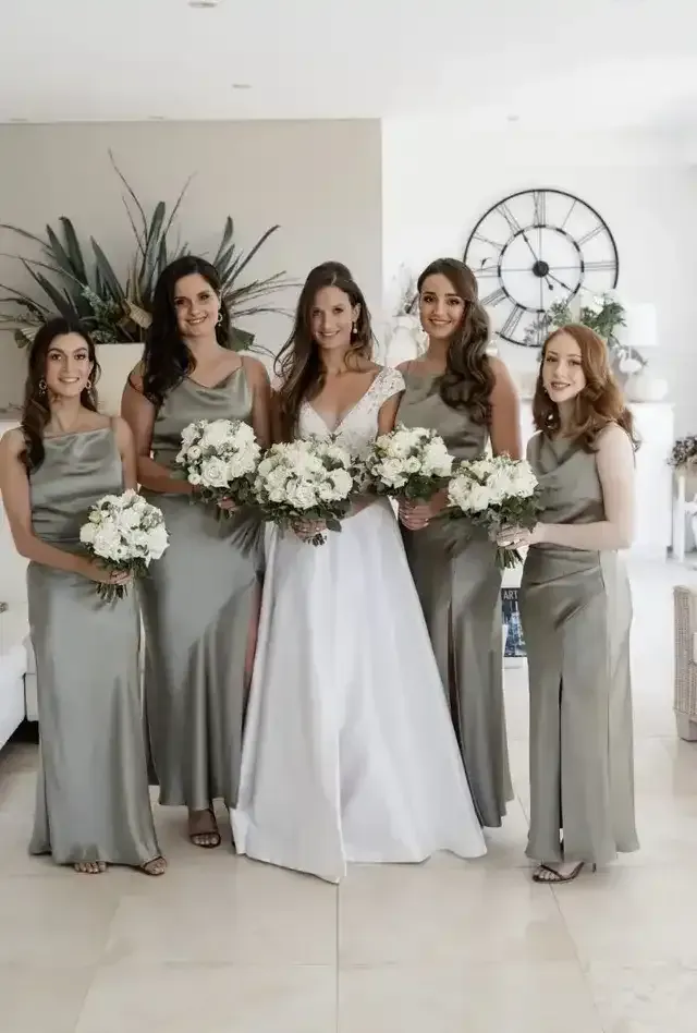 A bride and her bridesmaids are posing for a picture in a living room.