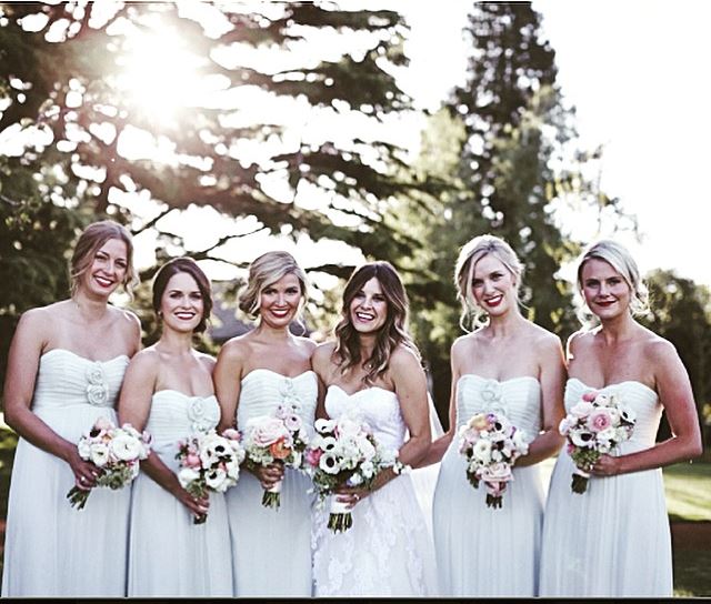 A bride and her bridesmaids are posing for a picture