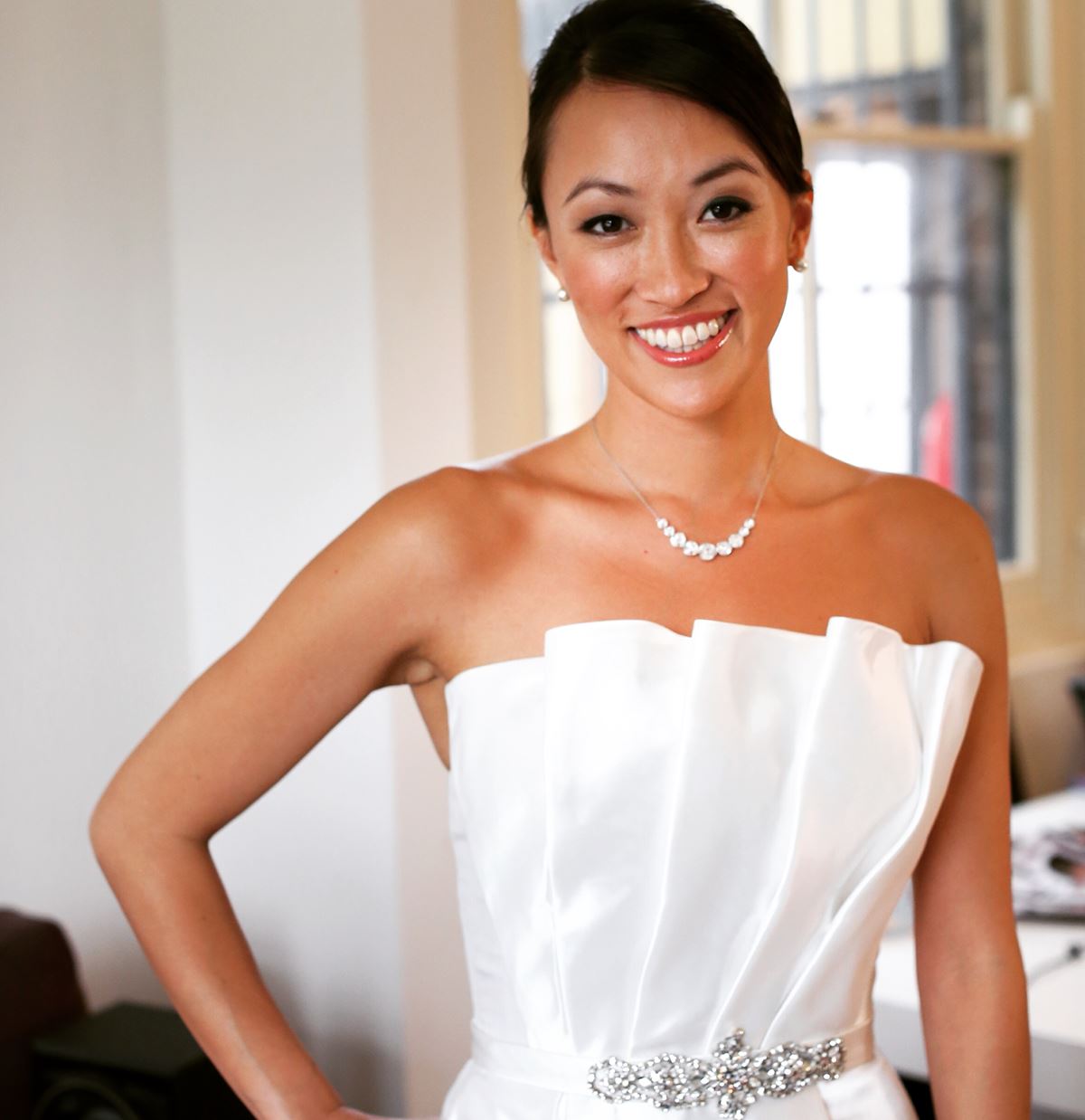 A woman in a white strapless dress smiles for the camera