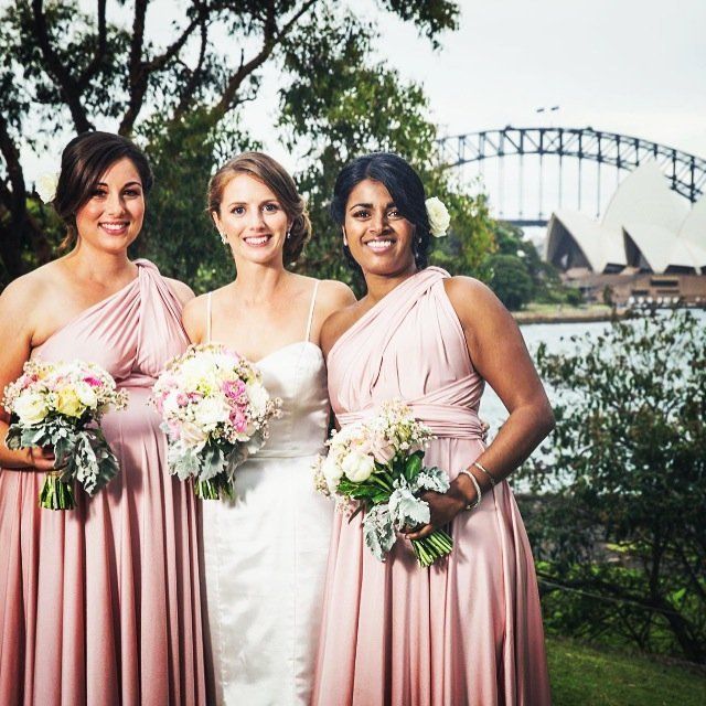 A bride and her bridesmaids pose in front of the opera house