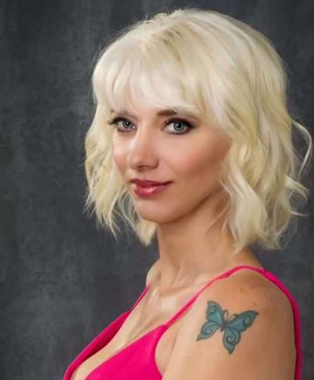 A woman with blonde hair and a butterfly tattoo on her shoulder.