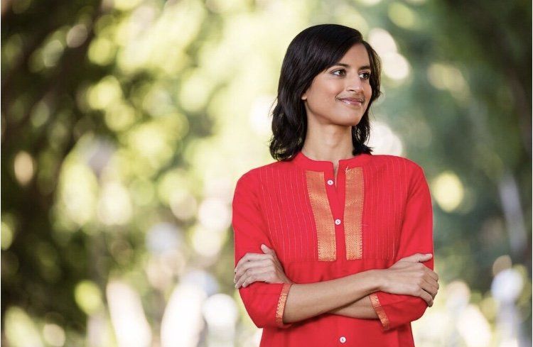 A woman in a red shirt is standing with her arms crossed