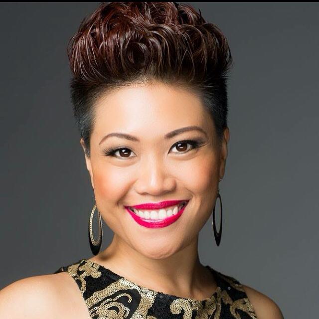 A woman with short hair and red lipstick is smiling for the camera.