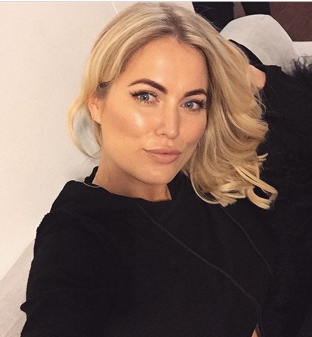 A woman with blonde hair is wearing a black shirt