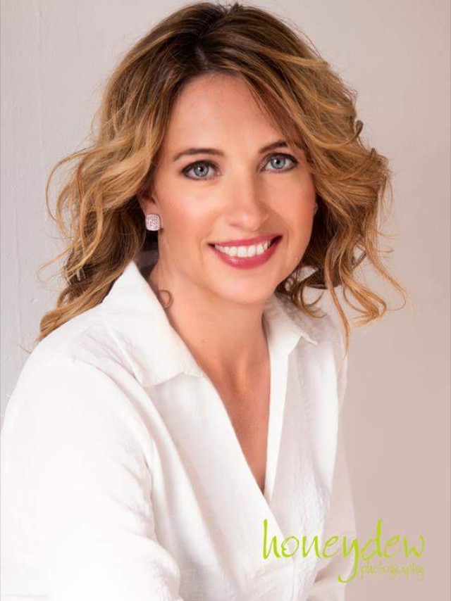 The woman is wearing a white shirt and smiling for the camera.