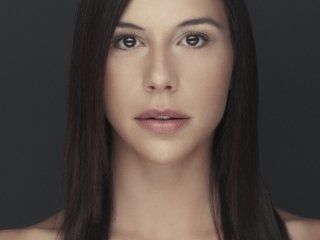 A close up of a woman 's face with long hair against a black background.