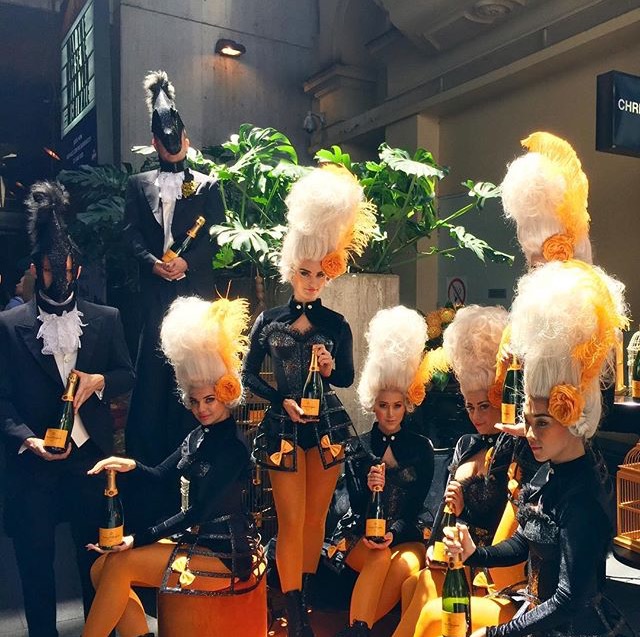 A group of people wearing wigs and holding bottles of champagne