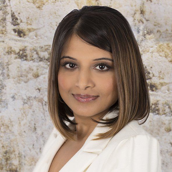 The woman is wearing a white jacket and smiling for the camera.