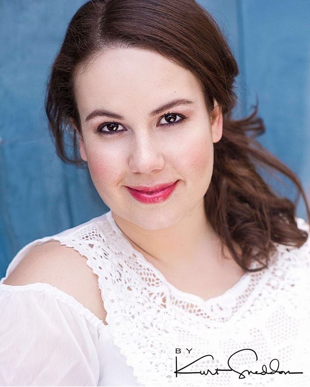 A woman in a white lace top is smiling for the camera