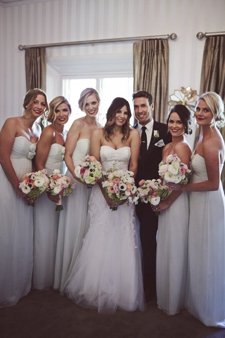 A bride and groom pose with their bridesmaids
