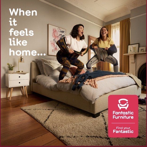 Two women jumping on a bed in a fantastic furniture ad