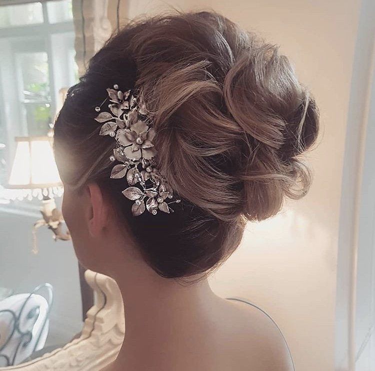 A woman is wearing a bun with a comb in her hair.