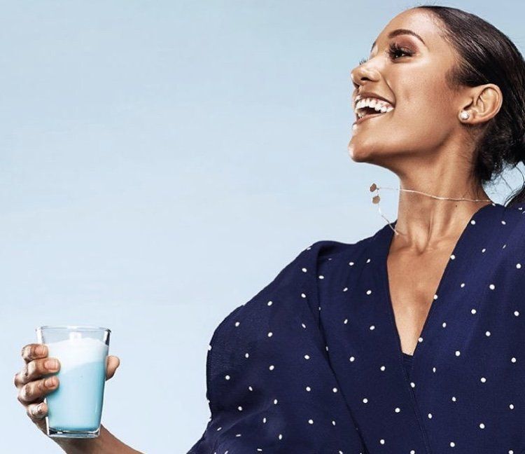A woman in a blue dress is holding a glass of milk