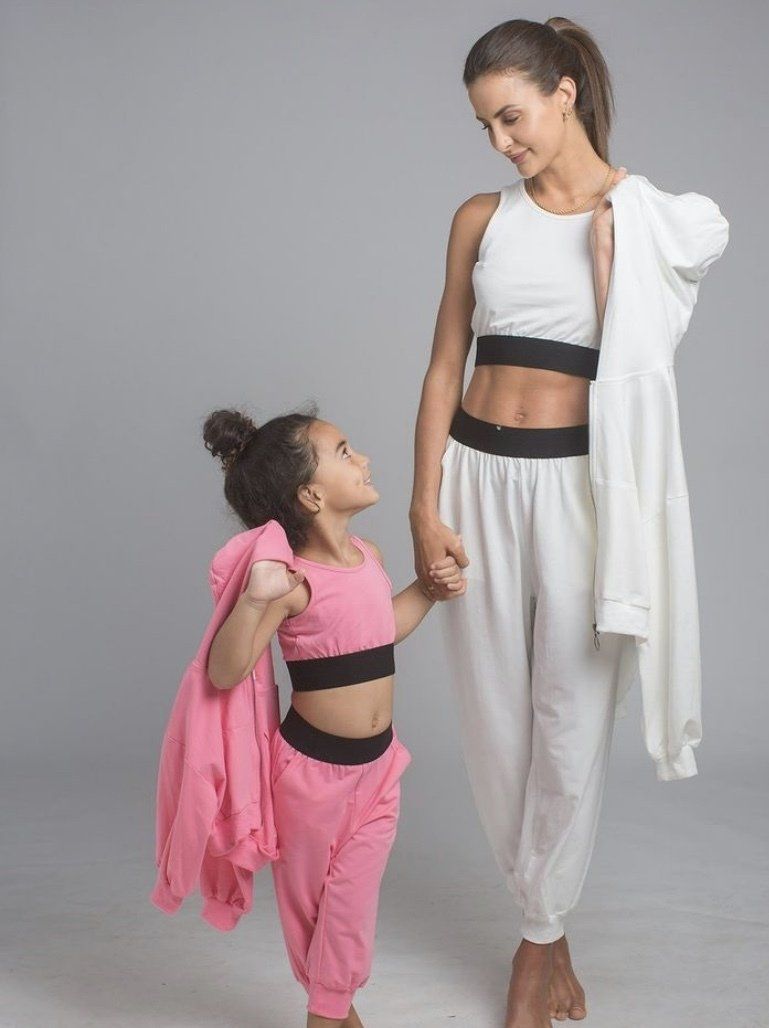 A woman and a little girl are holding hands while standing next to each other.