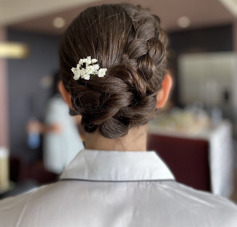 A woman with a braided bun has a flower in her hair