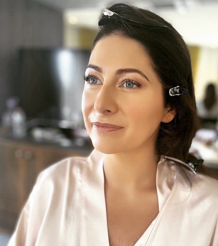 A woman is wearing a robe and getting her hair done.