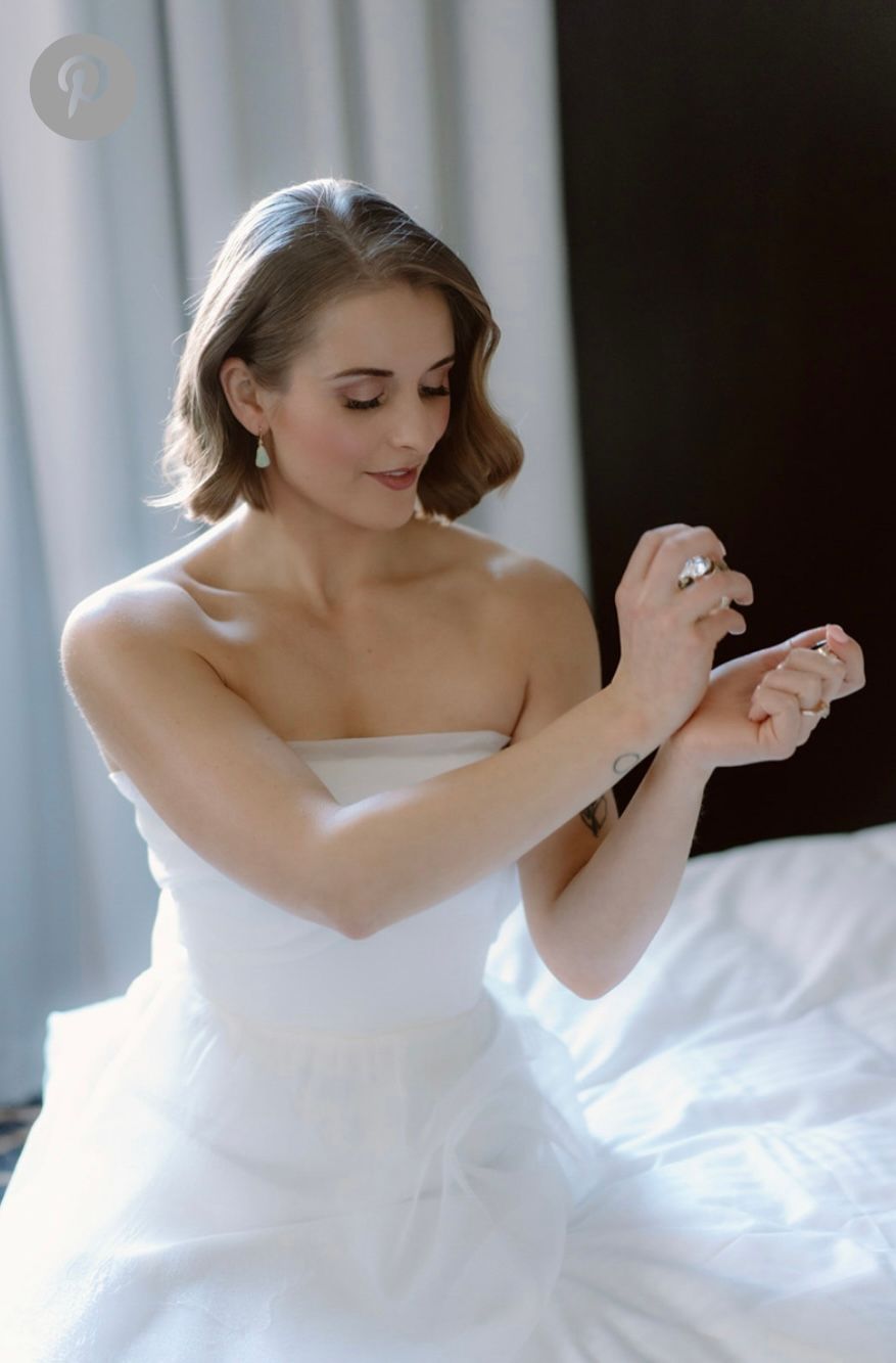 bride putting on perfume after having her hair and makeup done