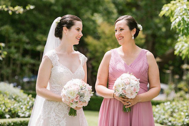 A bride and her bridesmaid are standing next to each other holding bouquets of flowers.