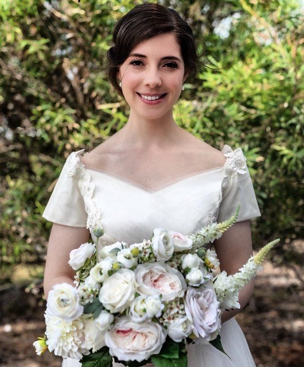 A woman in a wedding dress is holding a bouquet of white flowers.