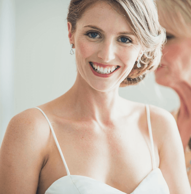 A woman in a white dress smiles for the camera