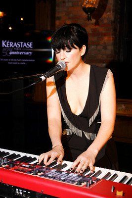 A woman singing into a microphone while playing a keyboard
