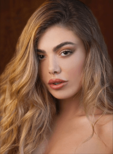 A woman with long blonde hair and red lips is looking at the camera.