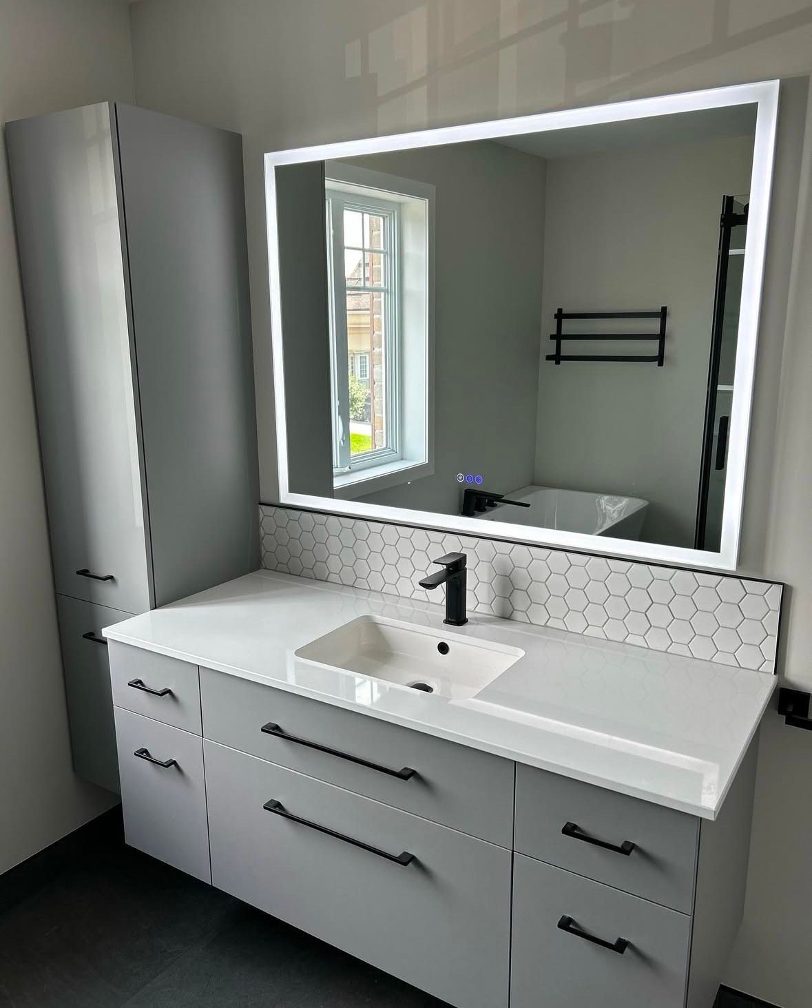 Une salle de bain avec lavabo, miroir et armoires.