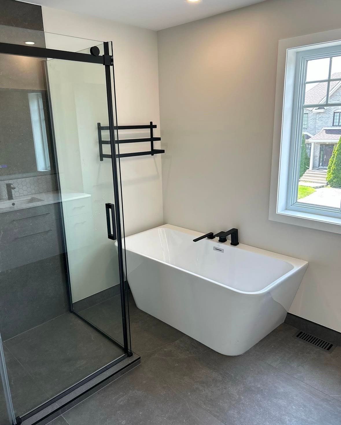 A bathroom with a bathtub , shower , sink and window.