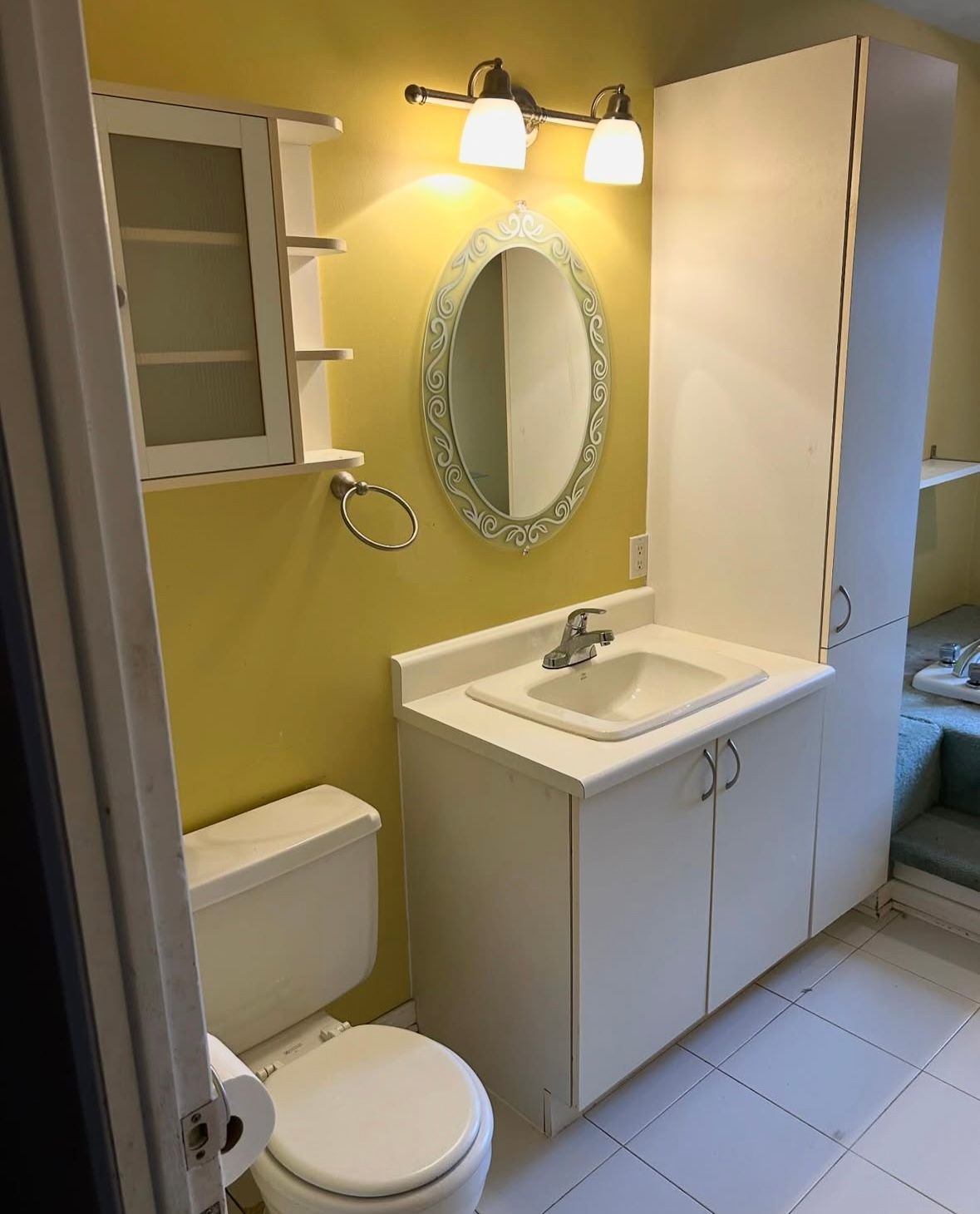 A bathroom with a toilet , sink , mirror and cabinets.