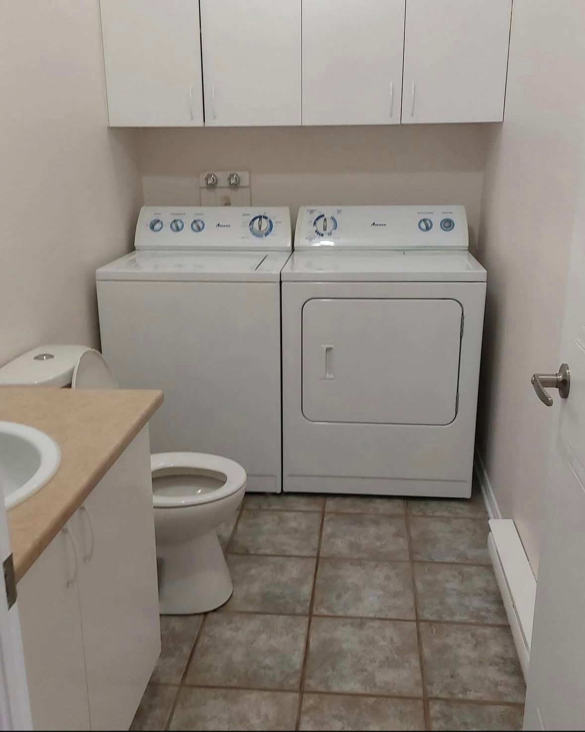 A bathroom with a washer and dryer and a toilet