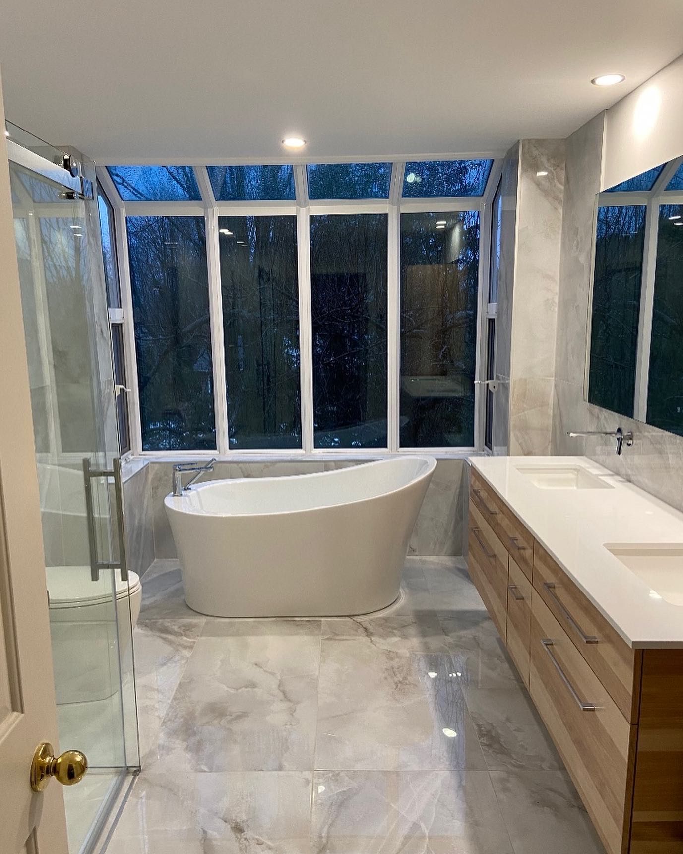 A bathroom with a tub , sinks , and a large window.