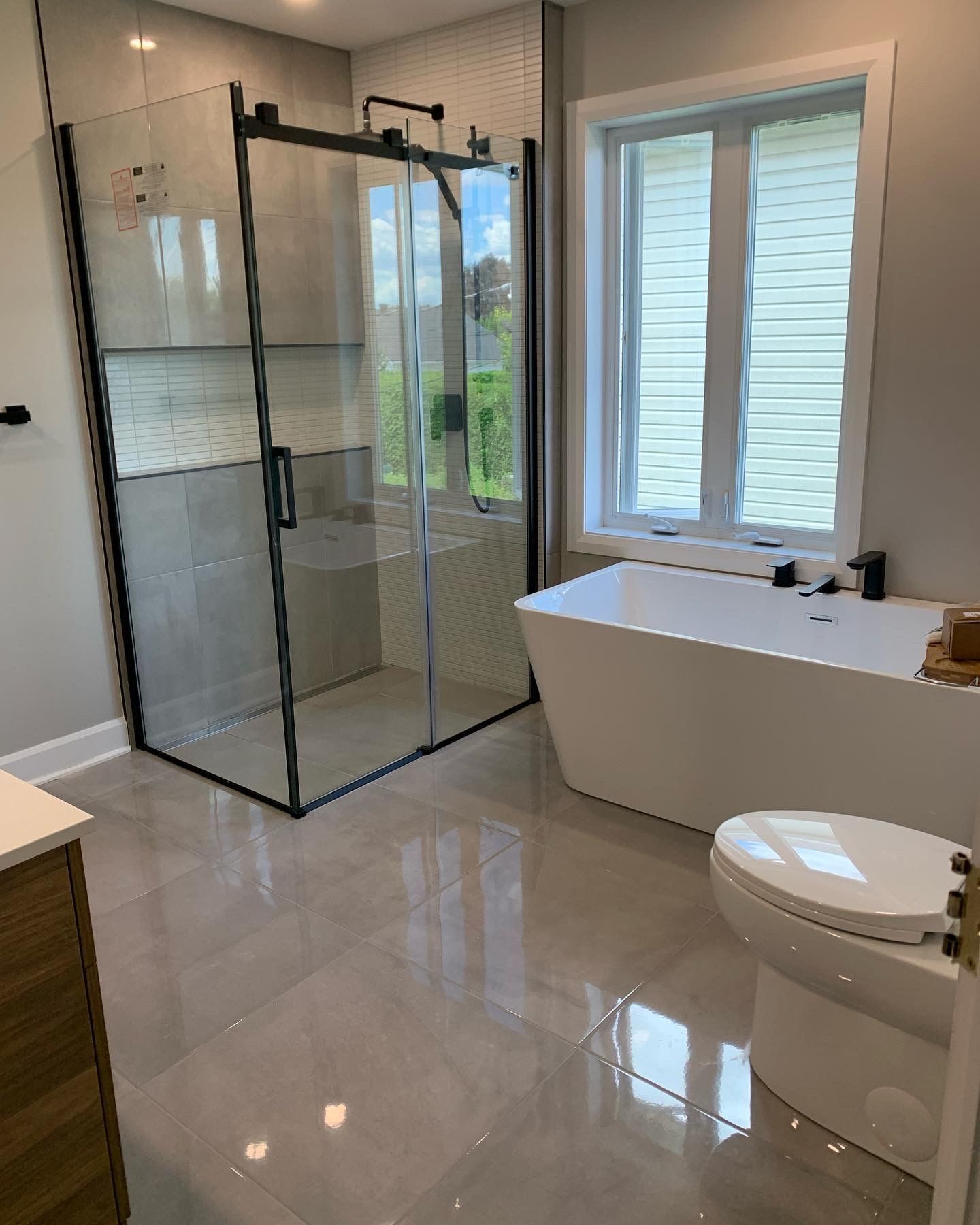 A bathroom with a tub , toilet , shower and window.