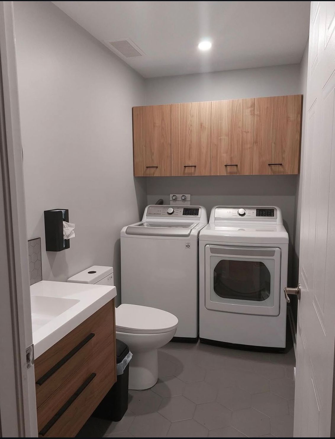 A laundry room with a washer and dryer , toilet , sink and cabinets.