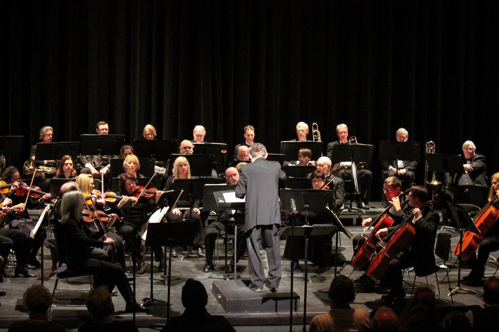 A man is leading an orchestra on a stage