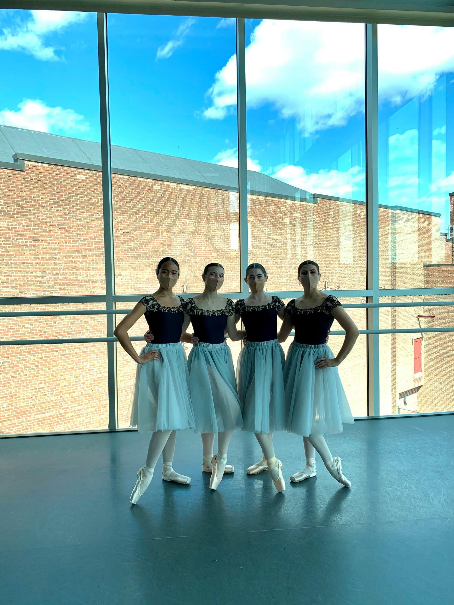 A group of young ballerinas are posing for a picture in a dance studio.