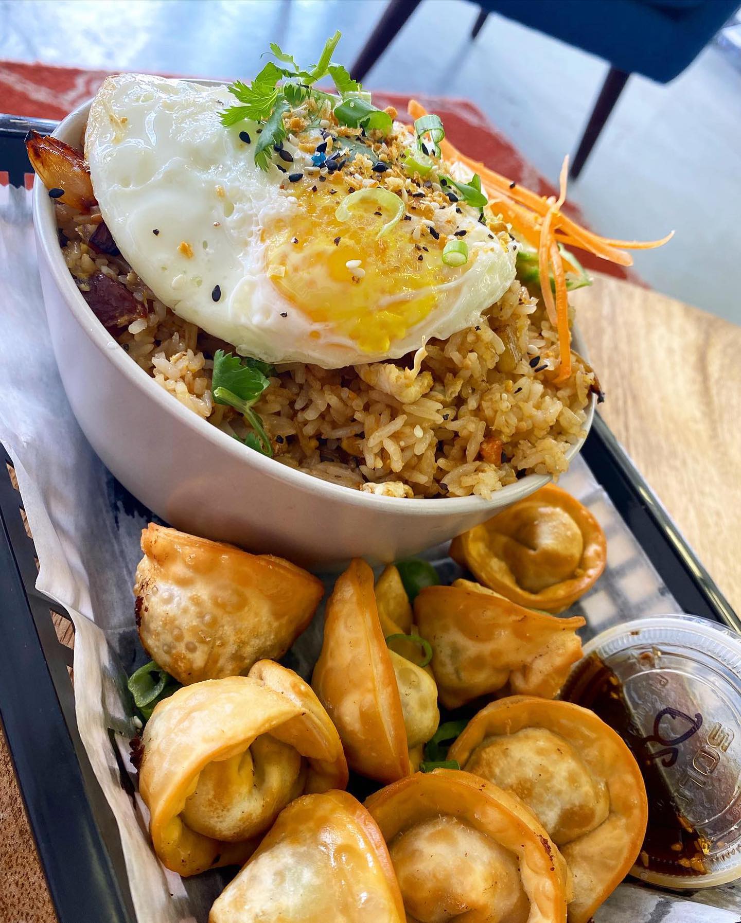 A bowl of fried rice and dumplings with a fried egg on top.