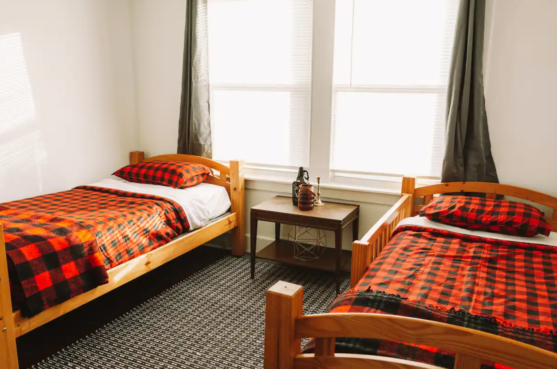 A bedroom with two beds , a table and two windows.