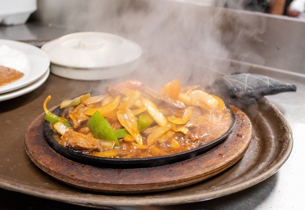 A close up of a plate of food on a tray with steam coming out of it.