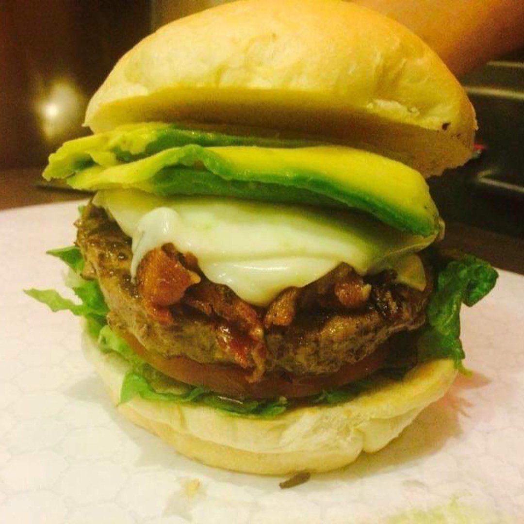 A hamburger with avocado and cheese on a bun